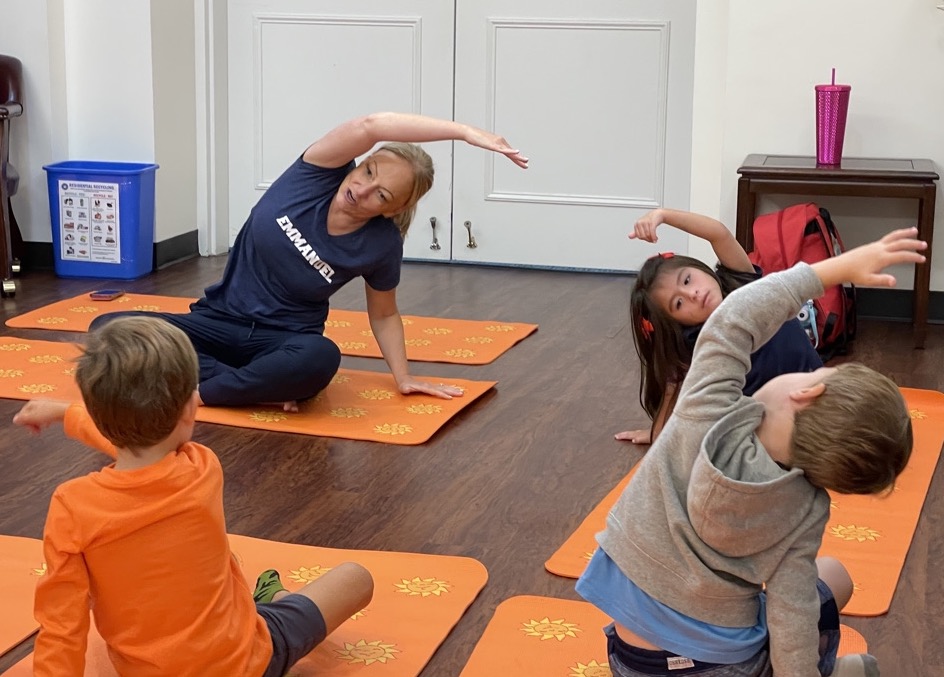 Ms. Meghan teaching a yoga class to preschoolers on orange mats